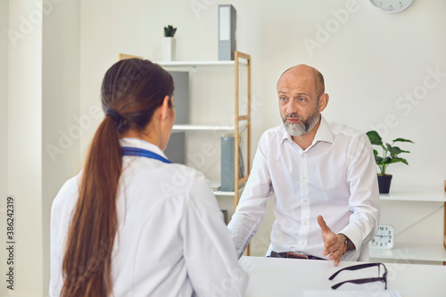 A middle-aged man talks to a doctor in the office. Medical consultation diagnosis prescription in a hospital
