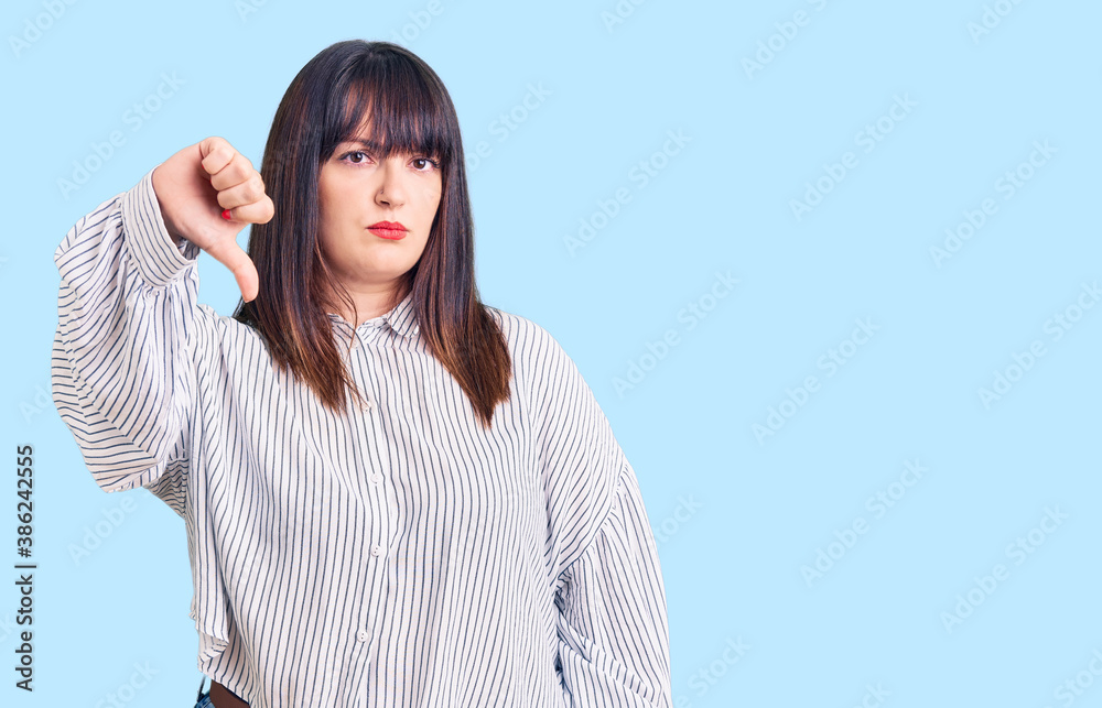 Young plus size woman wearing casual clothes looking unhappy and angry showing rejection and negative with thumbs down gesture. bad expression. Young plus size woman wearing casual clothes looking unhappy and angry showing rejection and negative with thumbs down gesture. bad expression.