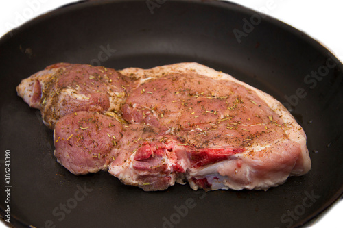 Fresh raw pork steak with spices roasting on frying pan