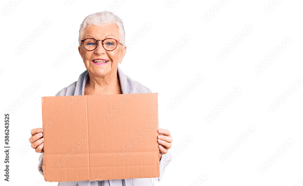 Senior beautiful woman with blue eyes and grey hair holding we need a change banner looking positive and happy standing and smiling with a confident smile showing teeth Senior beautiful woman with blue eyes and grey hair holding we need a change banner looking positive and happy standing and smiling with a confident smile showing teeth