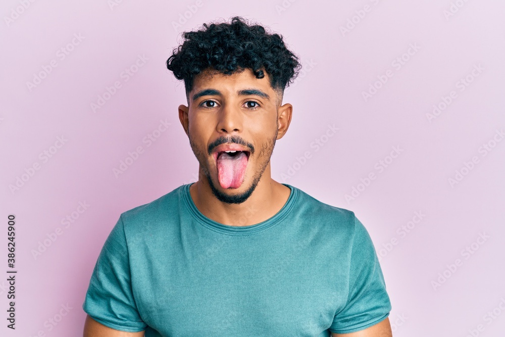 Young arab handsome man wearing casual clothes sticking tongue out happy with funny expression. emotion concept. Young arab handsome man wearing casual clothes sticking tongue out happy with funny expression. emotion concept.