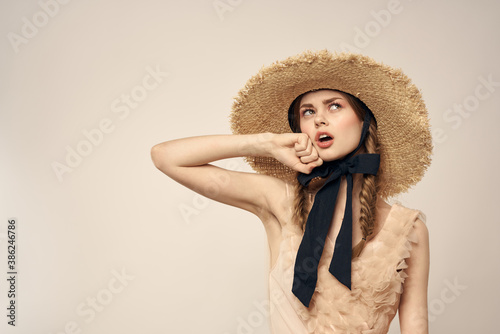 cute girl in straw hat with black ribbon and dress on beige background cropped view