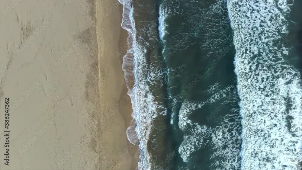 Top aerial view of beautiful sea waves breaking on sandy coastline. Aerial shot of beach meeting deep ocean water and foamy waves Top aerial view of beautiful sea waves breaking on sandy coastline. Aerial shot of beach meeting deep ocean water and foamy waves