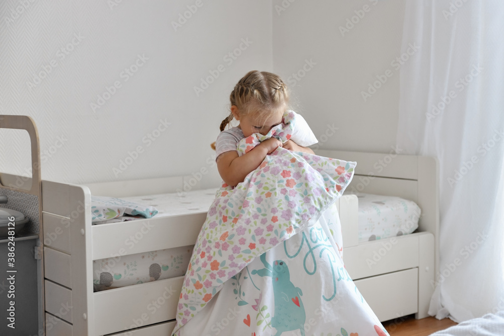 A girl makes a bed in the childrens room A girl makes a bed in the childrens room