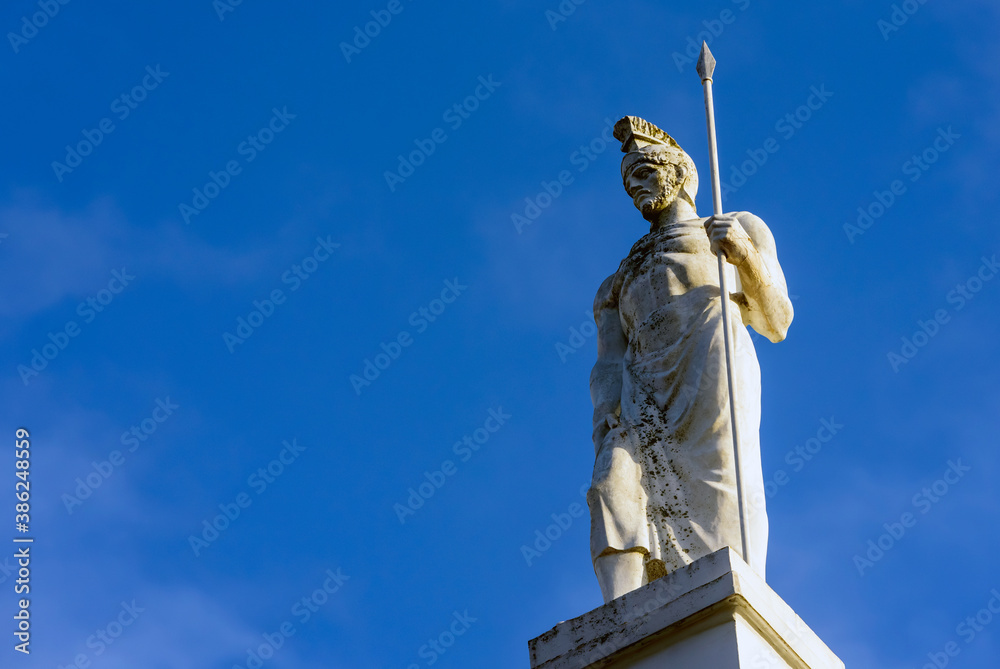 Sculpture and ancient Greek warrior with a spear against the sky.
