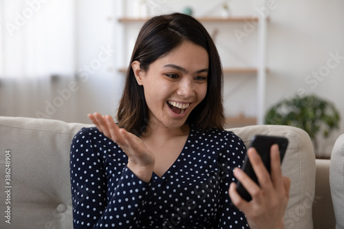 Happy young Asian woman look at cellphone screen feel excited euphoric with unexpected good message. Overjoyed millennial Vietnamese girl triumph get sale discount or offer on smartphone gadget.