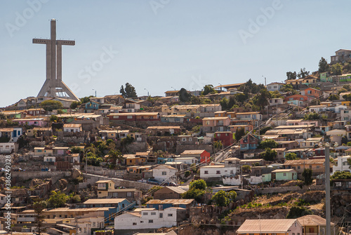 Coquimbo, Chile - December 7, 2008: Closeup of tall Millennium Cross Trinity surrounded by houses in different colors under blownish cloudscape. photo