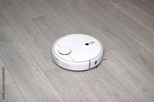 robot vacuum cleaner cleans the apartment. white robot vacuum cleaner in interior