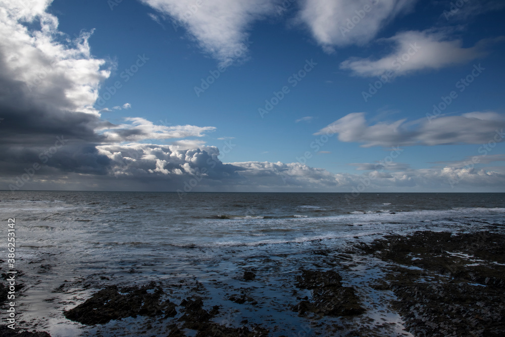 a view of cardigan bay from Aberystwyth. the view of the sea waves crashing against the small slate rocks on the floor