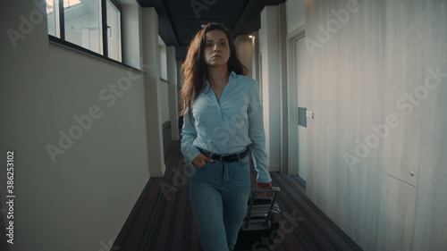 Pretty woman looking for hotel room. Determined girl pulling suitcase corridor