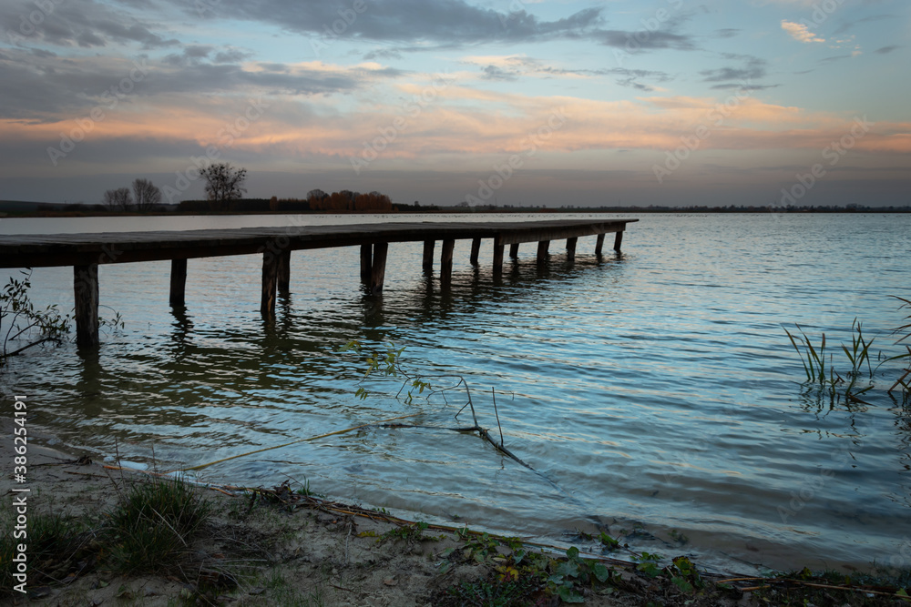 Wooden bridge towards the lake and dark evening clouds