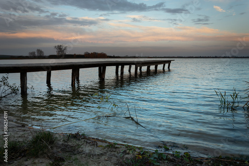 Wooden bridge towards the lake and dark evening clouds