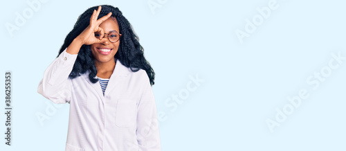 Beautiful african american optician woman with optometry glasses smiling happy doing ok sign with hand on eye looking through fingers photo