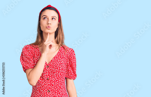 Young beautiful girl wearing dress and diadem thinking concentrated about doubt with finger on chin and looking up wondering