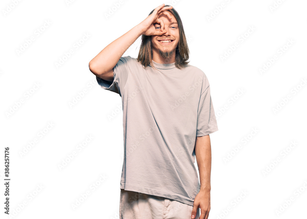 Handsome caucasian man with long hair wearing casual clothes doing ok gesture with hand smiling, eye looking through fingers with happy face.