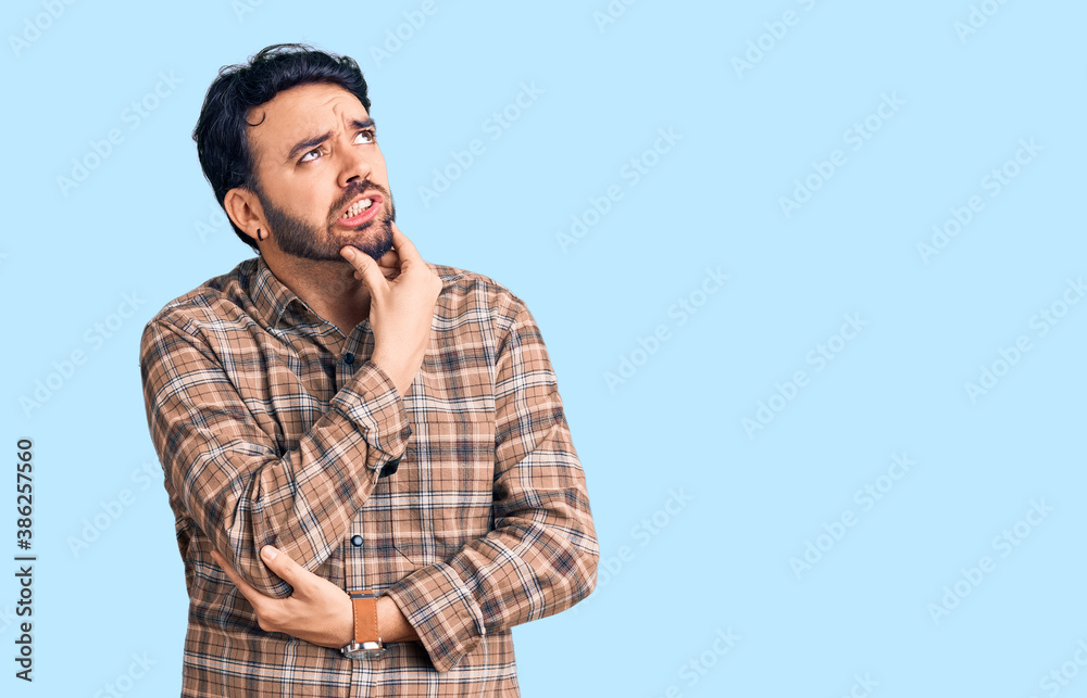 Young hispanic man wearing casual clothes thinking worried about a question, concerned and nervous with hand on chin