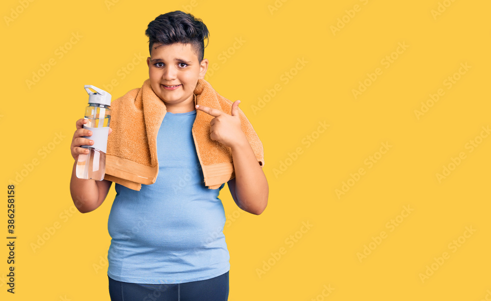 Little boy kid wearing sportswear drinking bottle of water smiling happy pointing with hand and finger Little boy kid wearing sportswear drinking bottle of water smiling happy pointing with hand and finger