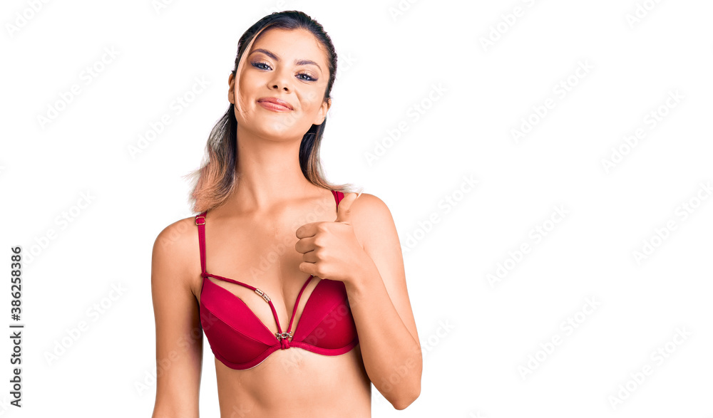 Young beautiful woman wearing bikini doing happy thumbs up gesture with hand. approving expression looking at the camera showing success. Young beautiful woman wearing bikini doing happy thumbs up gesture with hand. approving expression looking at the camera showing success.