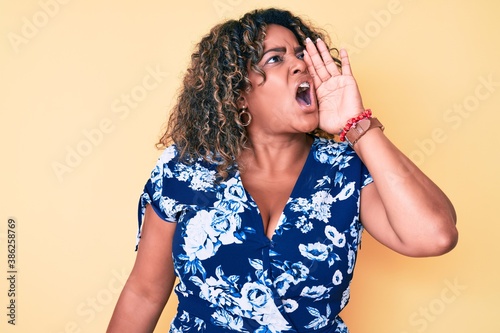 Young african american plus size woman wearing casual clothes shouting and screaming loud to side with hand on mouth. communication concept.