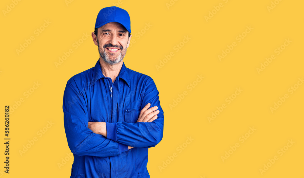 Middle age handsome man wearing mechanic uniform happy face smiling with crossed arms looking at the camera. positive person.