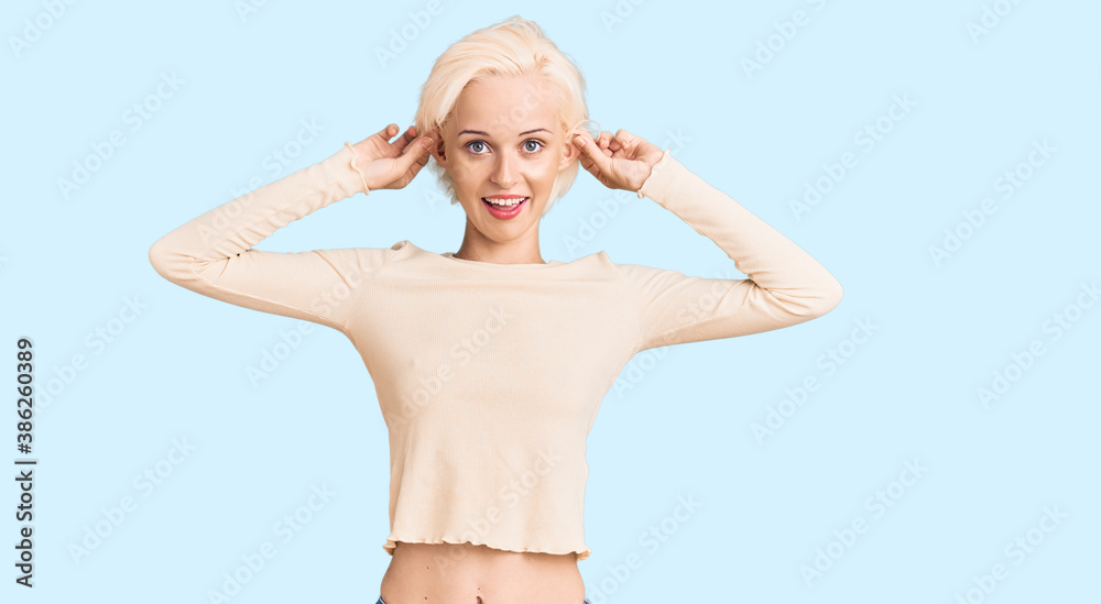 Obraz premium Young blonde woman wearing casual clothes smiling pulling ears with fingers, funny gesture. audition problem