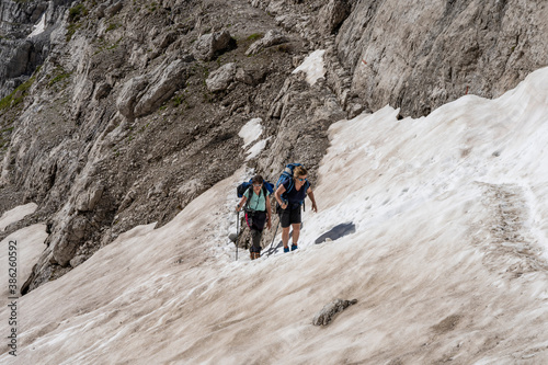 two experienced female hikers are climbing a snowy valley in the Dolomites