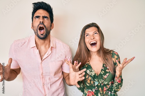 Beautiful young couple of boyfriend and girlfriend together crazy and mad shouting and yelling with aggressive expression and arms raised. frustration concept.