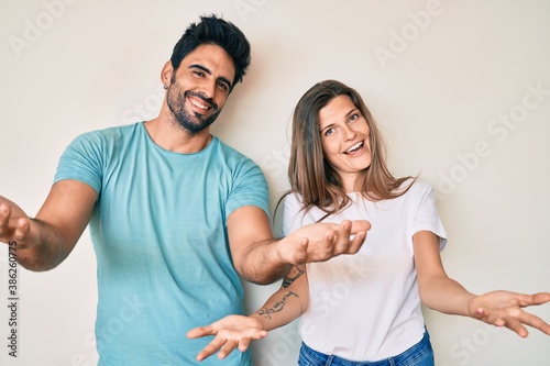 Beautiful young couple of boyfriend and girlfriend together smiling cheerful offering hands giving assistance and acceptance.