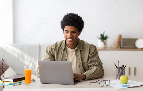 E-learning concept. African American teenager studying online on laptop computer at home