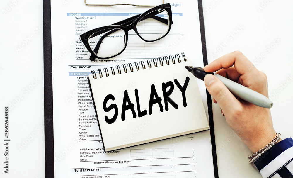 Salary text on notepad, woman hand with marker. Business concept