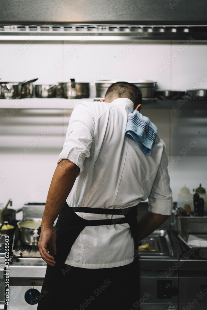 Portrait of a male chef backwards cooking in a restaurant kitchen. Portrait of a male chef backwards cooking in a restaurant kitchen.