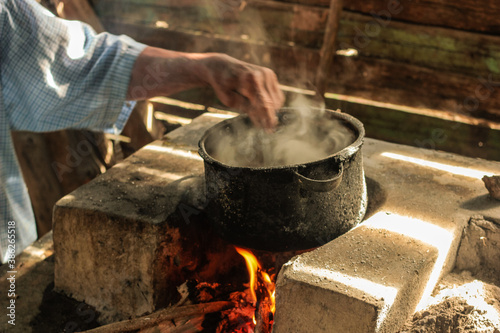 RURAL KITCHEN IN RUSTIC WOODEN HOUSE, WITH POT ON THE HOT FIRE