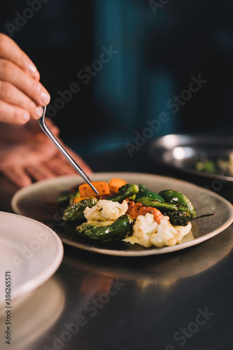 Wallpaper Mural Close-up of the hands of a male chef decorating with carrot in ceramic dish over stainless steel worktop in restaurant kitchen. Torontodigital.ca