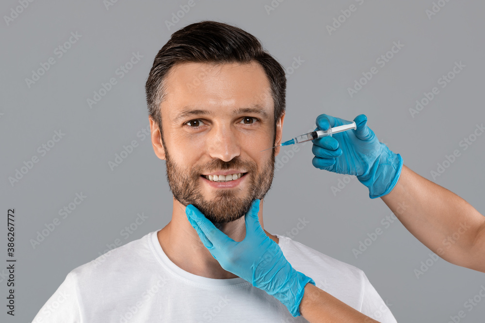 Cosmetician injecting face filler for middle-aged man Cosmetician injecting face filler for middle-aged man