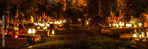 Many lit grave lights on All Saints' Day. Grave memorial candles in the cemetery. Cemetery alley at night. 