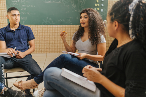 Latin students in the classroom. students doing group study. curly hair female student talking