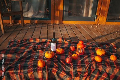 Pumpkins and bottle of red wine with two glasses on the blanket