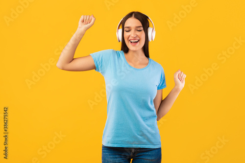 Smiling woman enjoying music with headphones and dancing
