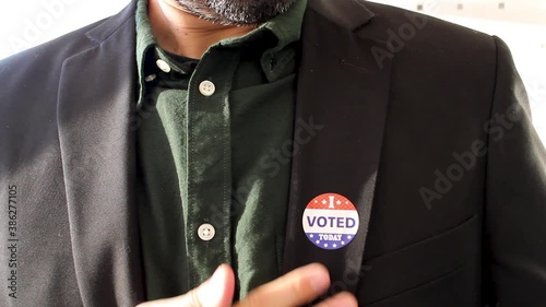 Close-up of man putting a I voted sticker on his coat