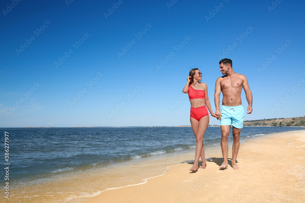 Woman in bikini and her boyfriend on beach, space for text. Happy couple Woman in bikini and her boyfriend on beach, space for text. Happy couple