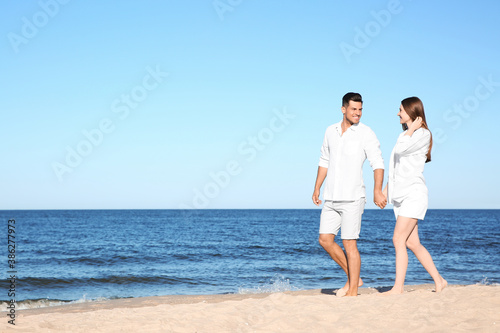 Lovely couple walking on beach. Space for text