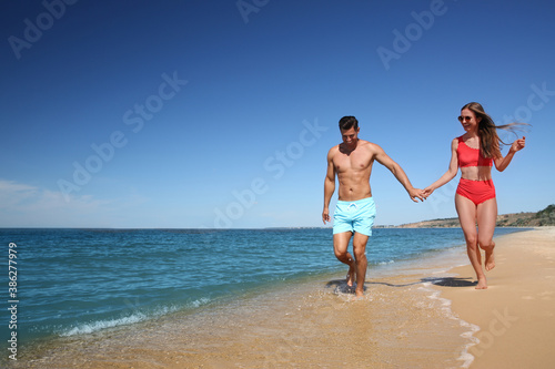 Woman in bikini and her boyfriend on beach  space for text. Happy couple