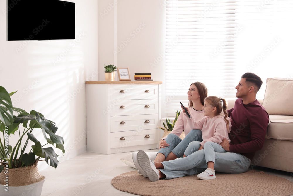 Fototapeta premium Happy family watching TV on floor at home