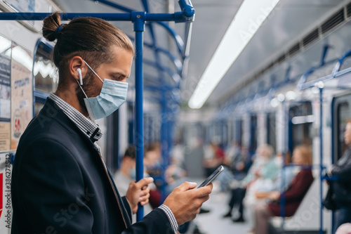 man in a protective mask standing in a subway car.