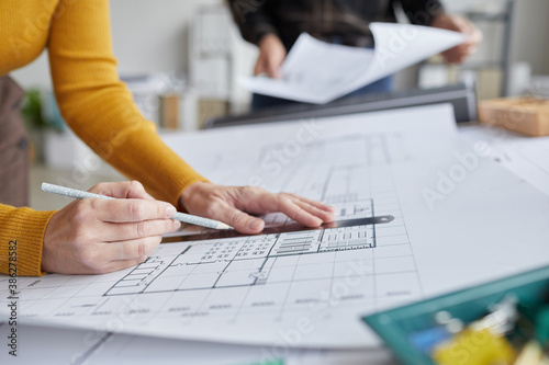 Close up of unrecognizable female architect drawing blueprints while working at desk in office, copy space