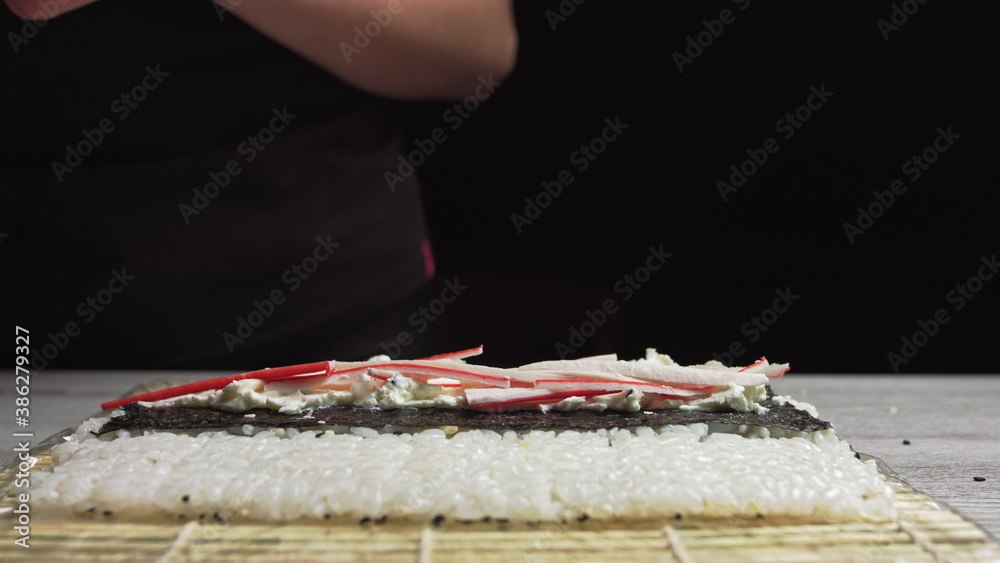 Close-up of Sushi Chef Hands puts crabs on a nori leaf and crab meat.Sushi making process.Rolls the sushi roll Close-up of Sushi Chef Hands puts crabs on a nori leaf and crab meat.Sushi making process.Rolls the sushi roll