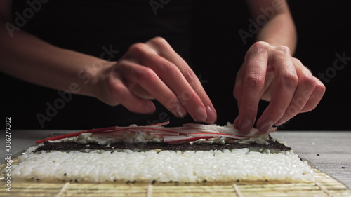 Close-up of Sushi Chef Hands puts crabs on a nori leaf and crab meat.Sushi making process.Rolls the sushi roll