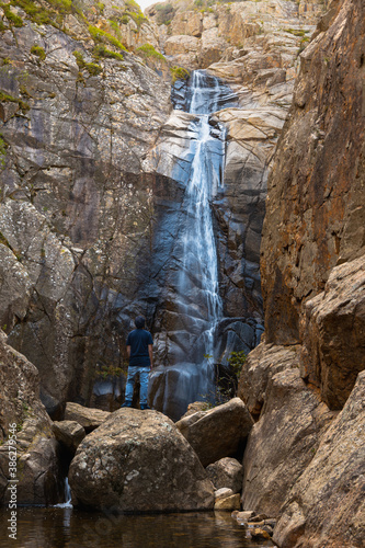 Frontal view of a young tourist sitting on a rock near Sa Spendula waterfall watching from below photo