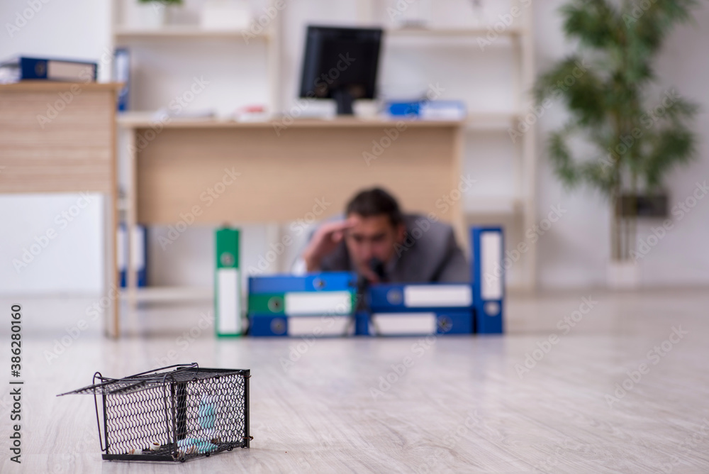 Young male employee and mousetrap in the office Young male employee and mousetrap in the office