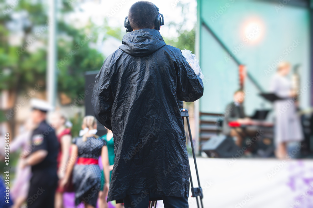 View of a camera man operator working during tv reportage, online broadcasting of concert, professional videographer with camera filming live event